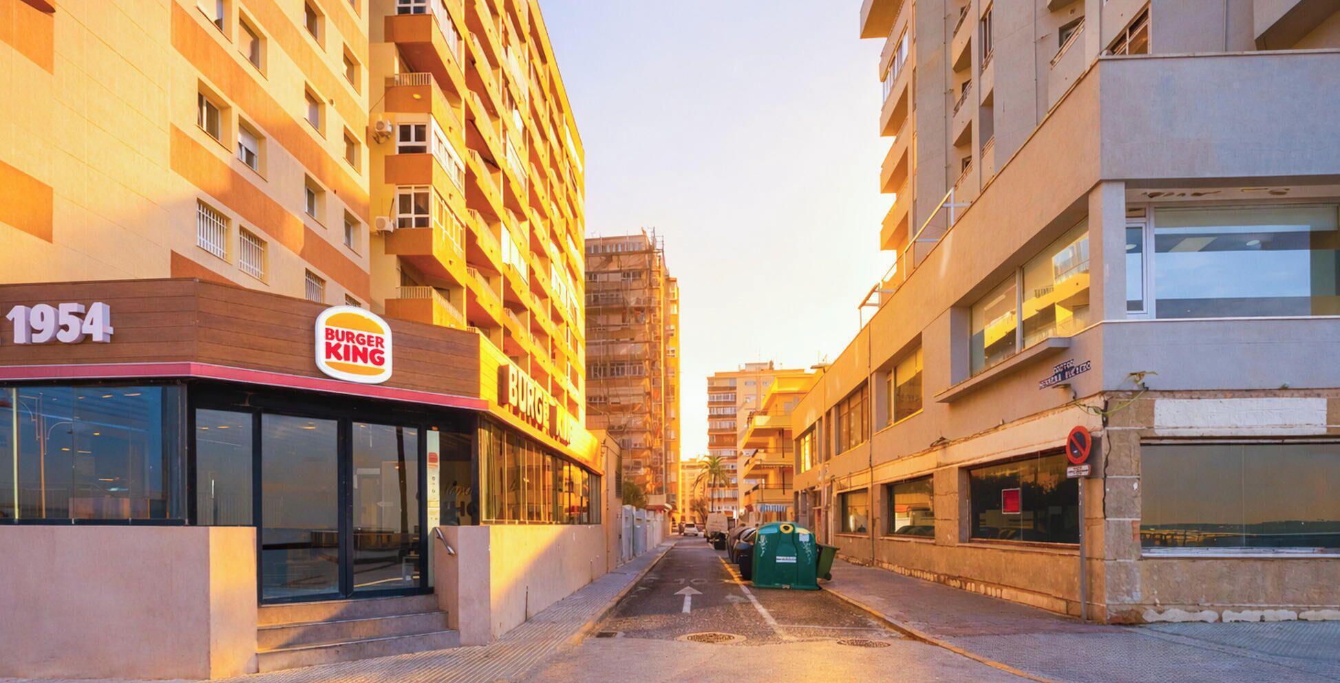 Een Burger King restaurant met een bord waarop '1954' staat, omringd door hoge gebouwen.