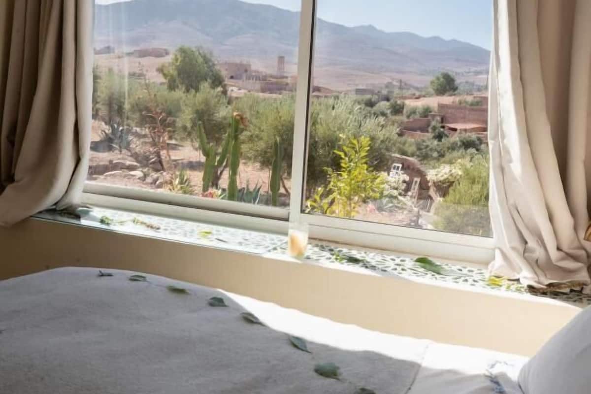 Ein Schlafzimmer mit einem großen Fenster und Blick auf eine Wüstenlandschaft mit Bergen.