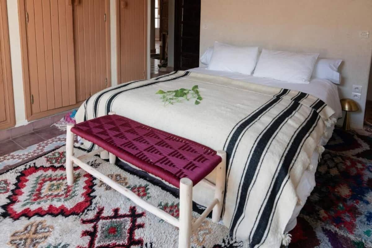 Ein Bett mit einer gestreiften Decke, eine Bank und ein gemustertes Teppich.