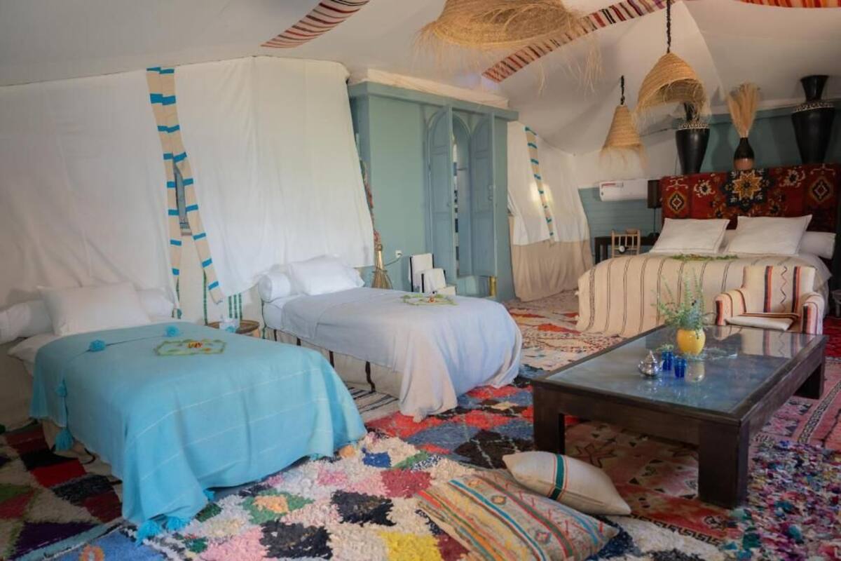 Ein Zimmer mit zwei Betten, einem Schlafsofa, einem Couchtisch und einem gemusterten Teppich.