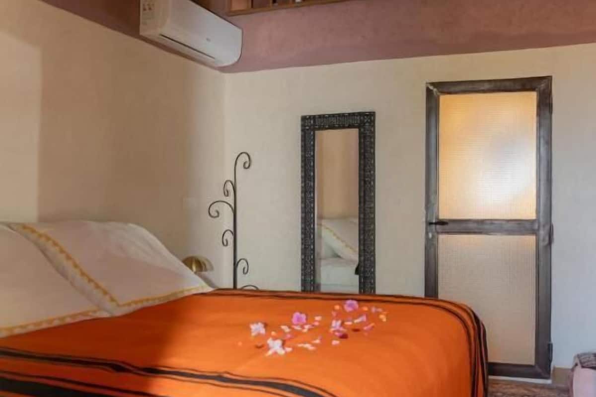 Ein Schlafzimmer mit Bett, Spiegel, Fenster und einer Treppe.
