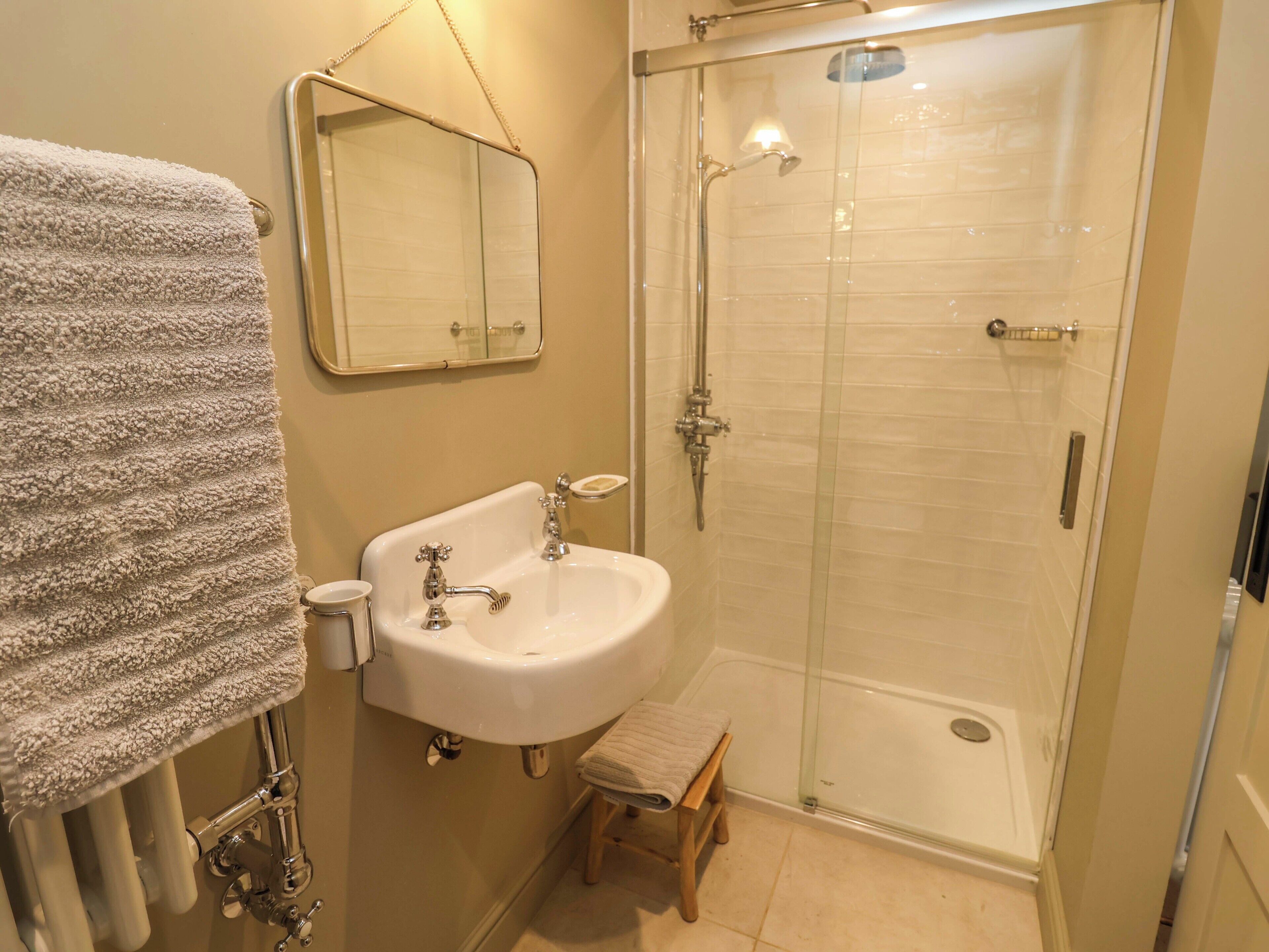 A bathroom with a glass-enclosed shower, a sink with a mirror above it, and a towel rack.