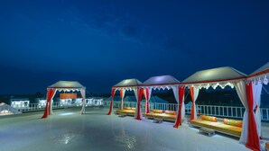 Une terrasse sur le toit dotée de plusieurs espaces salon, chacun étant agrémenté d’un auvent et de coussins.