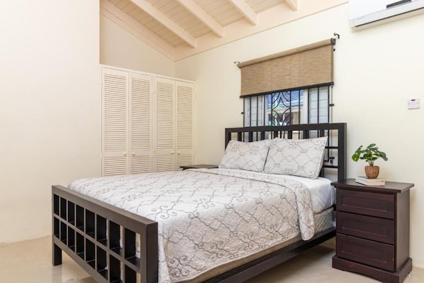 A bedroom with a bed, a nightstand, a potted plant, a window with blinds, and a white wardrobe. - 3 Bedroom Cozy House in Drax Hall (Ocho Rios)