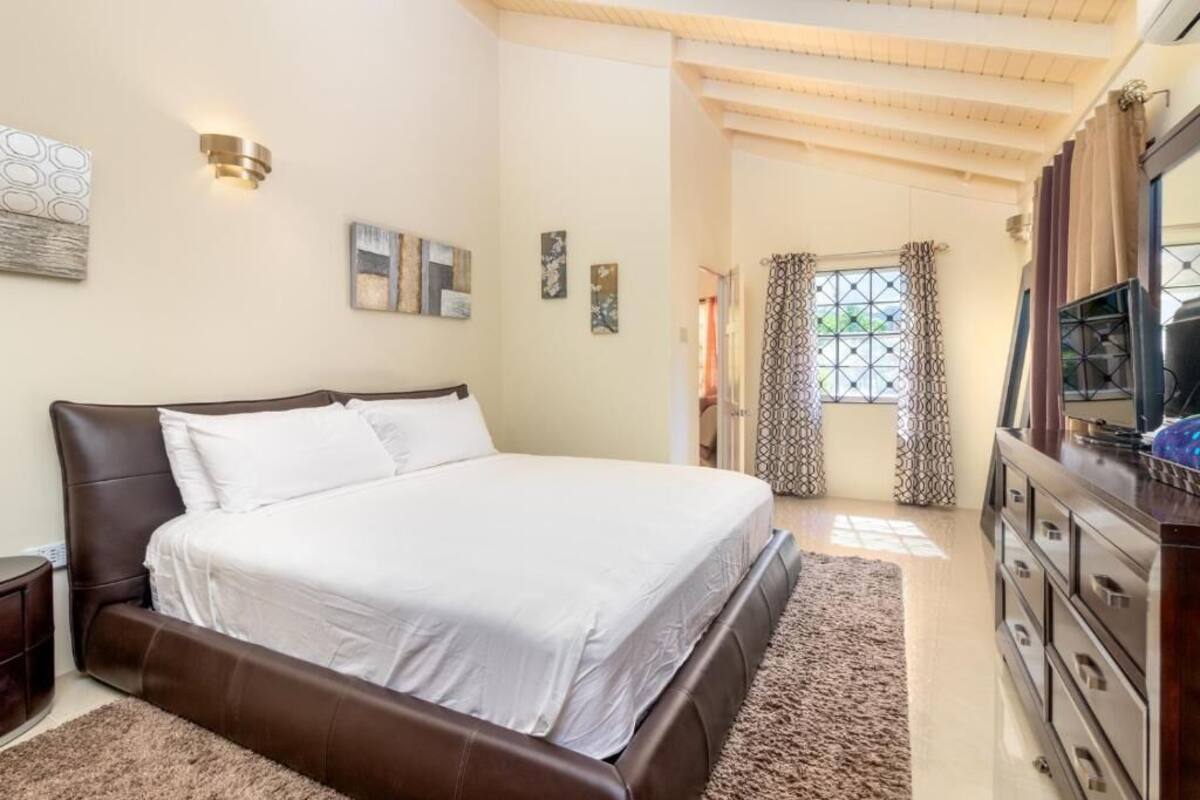 A bedroom with a large bed, a dresser, and a mirror.