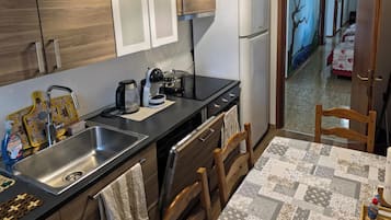 A modern kitchen with a stainless steel sink, a coffee maker, and a refrigerator.