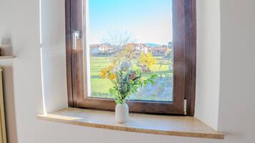 Una habitación con ventana, con marco de madera y una pequeña estantería debajo.