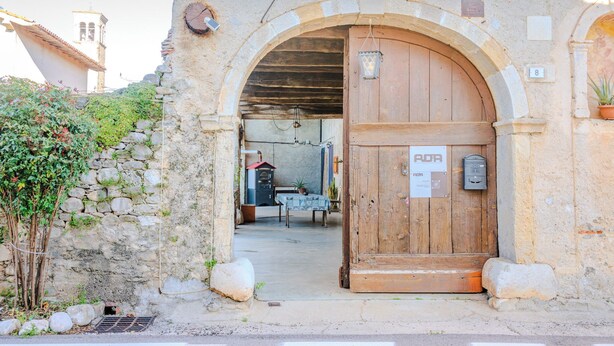 An arched entrance with a wooden door, a stone wall, and a small table with a tablecloth. - Dimora del 700' (Premariacco)