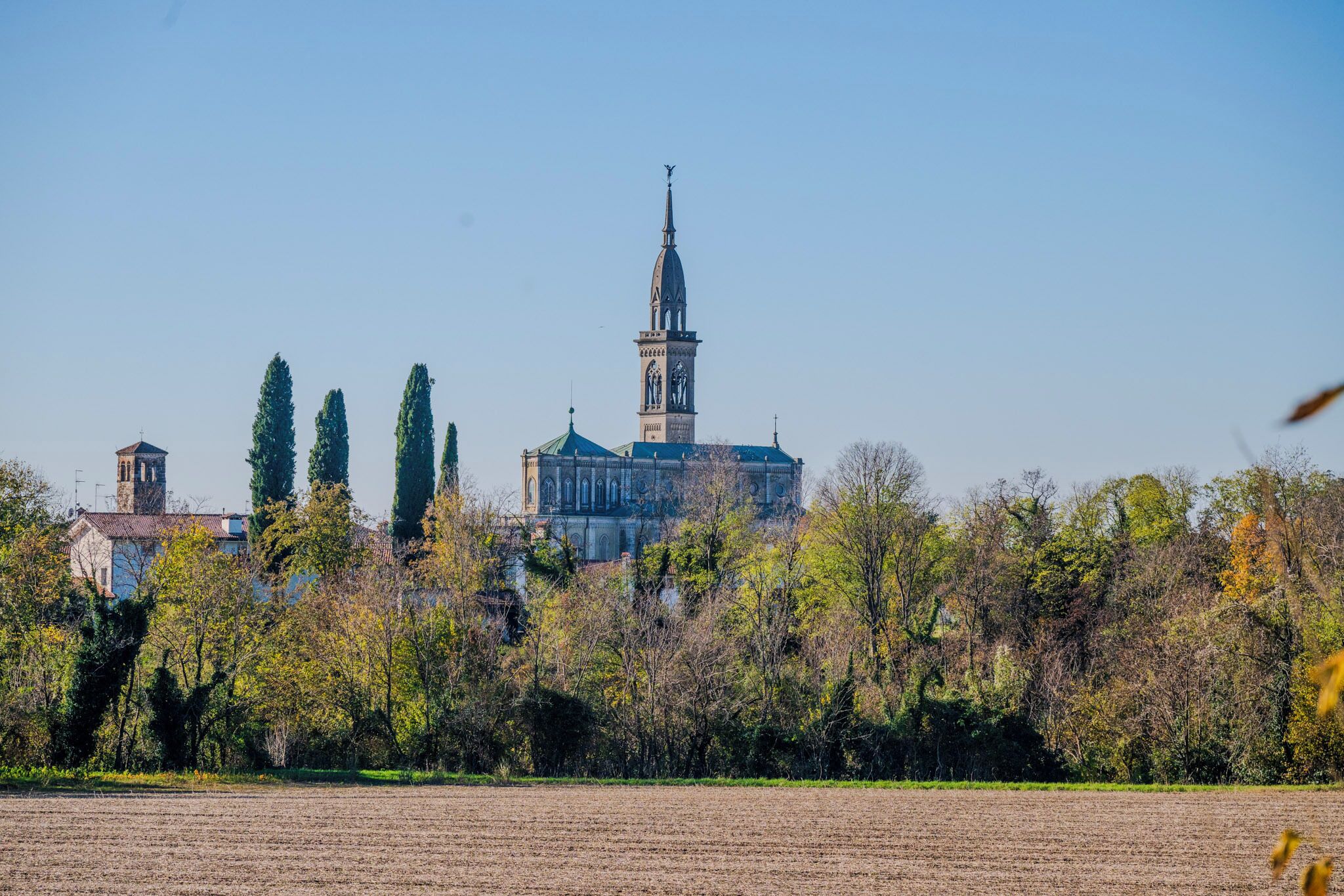 A historic building with a prominent tower and a large open field in the foreground.