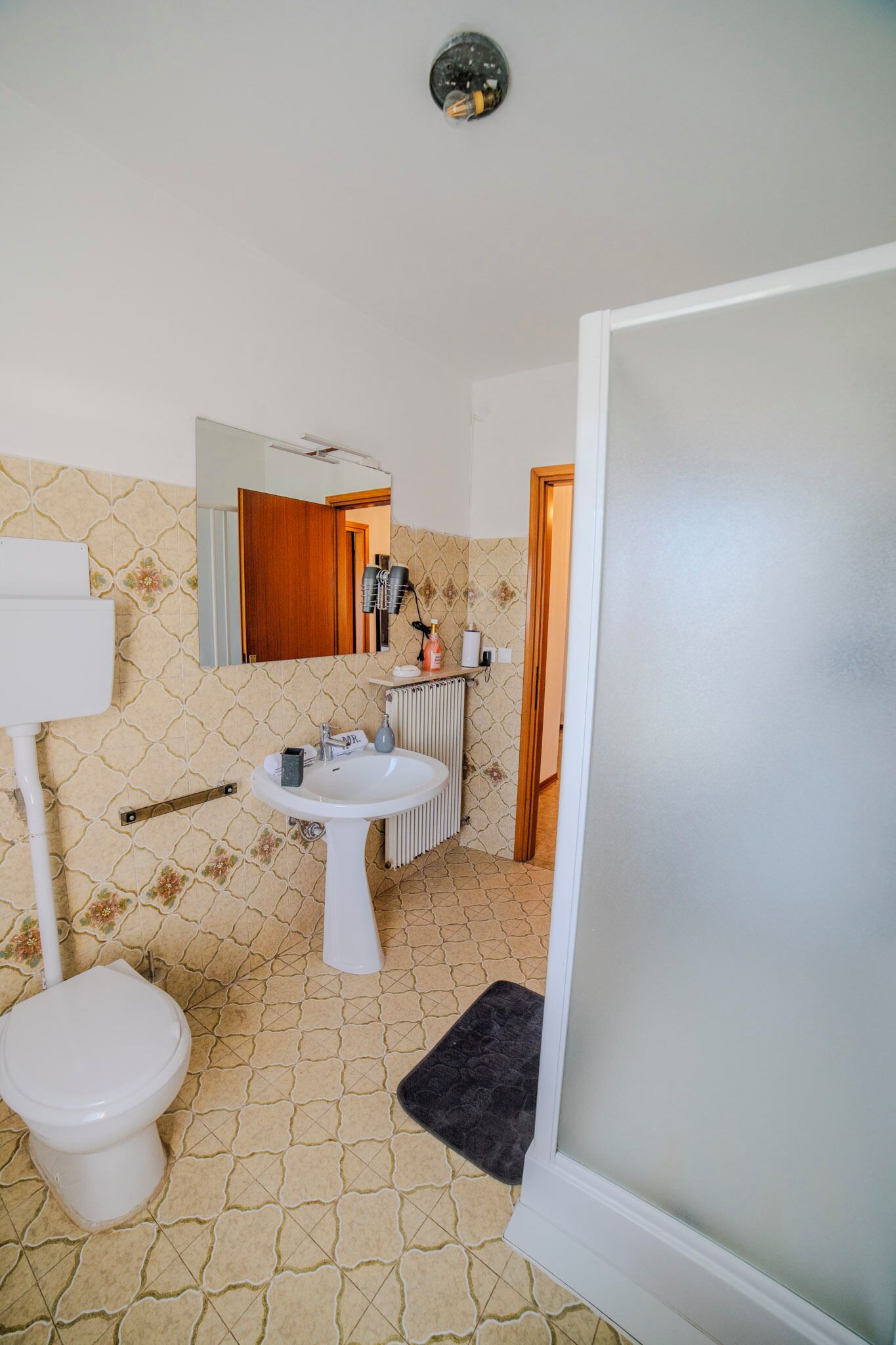 A bathroom with a toilet, sink, and mirror.