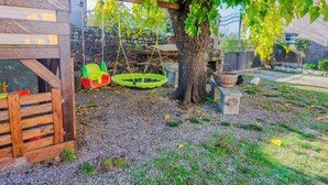 A wooden playhouse with a swing set, a tree, and a fenced garden area. - Dimora del 700' (Premariacco)