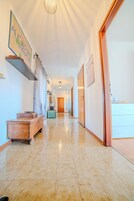 Un pasillo de hotel con un banco de madera, una maleta y un cuadro en la pared.