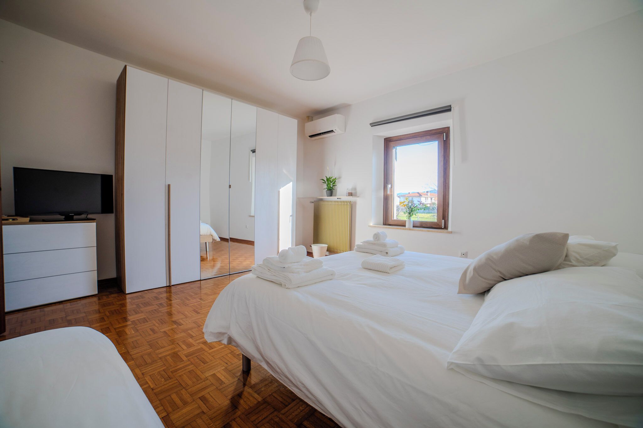 A bedroom with a bed, a TV, a wardrobe, and a window.