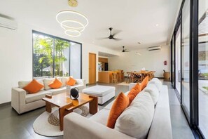 A modern hotel lobby with a sofa set, a coffee table, and a dining area. - Villa Talun by GORO (Kabupaten Gianyar)