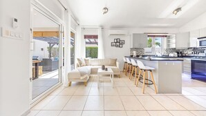 Une cuisine moderne dotée d’un îlot central, de tabourets de bar et d’un coin repas comprenant un canapé et une table basse.