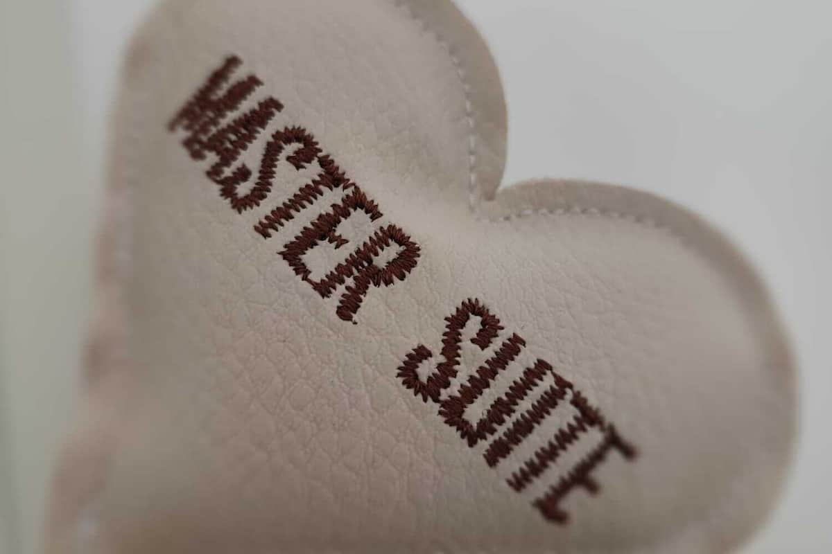 A heart-shaped keychain with the text "MASTER SUITE" embroidered on it.