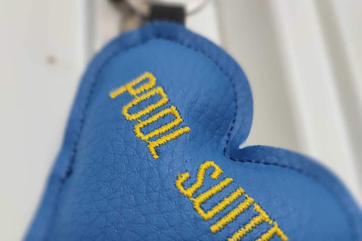 A blue keychain with the text "POOL SUITE" embroidered on it.