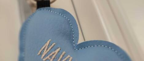 A blue heart-shaped keychain with the word "NAVY" embroidered on it.