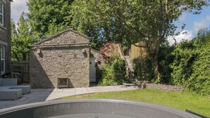 A stone building with a door and steps leading to a hot tub area. - Rocklands (Penrith)