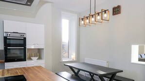 A modern kitchen with a wooden table, black benches, and a built-in oven. - Rocklands (Penrith)