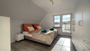 Ein Schlafzimmer mit Bett, Nachttisch und Blick durch ein Fenster.