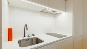 Eine moderne Küche mit Spüle aus Edelstahl, einem Zweifach-Wasserhahn und einem eingebauten Backofen.