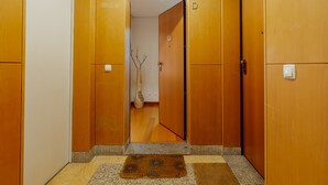 A hallway with wooden doors, a doormat, and a vase with branches. - Downtown Deluxe 3 by Vacationy (Porto)