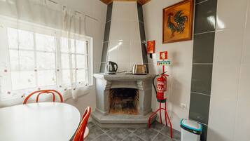 A kitchen with a stone fireplace, a fire extinguisher, a table, and chairs.