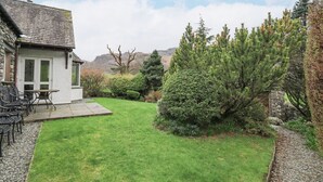 A house with a stone exterior, a grassy yard, and a patio with outdoor furniture. - Thrang View (Ambleside)