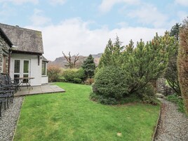 Una casa con fachada de piedra, césped y un patio con muebles de exterior.