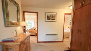 A hallway with a wooden dresser, a lamp, a framed picture on the wall, and a radiator. - Thrang View (Ambleside)