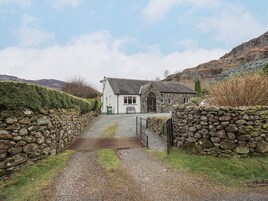 Una casa de piedra con un camino de grava que lleva a una verja.