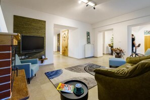 Ein modernes Wohnzimmer mit einem Flachbildfernseher, blauen Sofas, einem Couchtisch und einem Bücherregal.