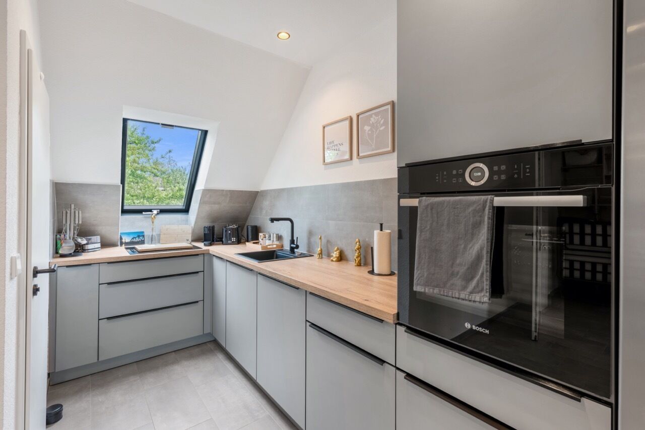 Una cocina moderna con horno integrado, ventana y pileta.