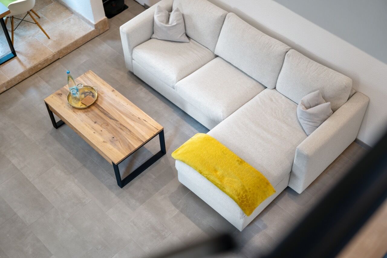 A modern living room with a light-colored sofa, a wooden coffee table, and a yellow throw pillow.