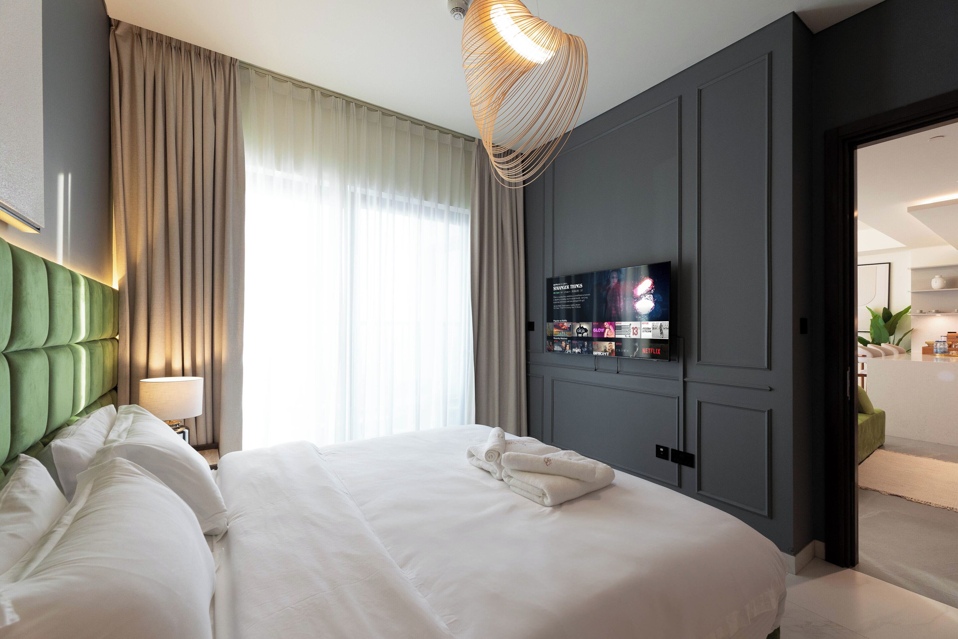 Camera d'albergo moderna con un letto grande, una TV a schermo piatto fissata al muro e vista sul bagno comunicante.