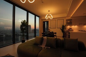 Ein modernes Wohnzimmer mit großem Fenster, Essbereich und Küche.