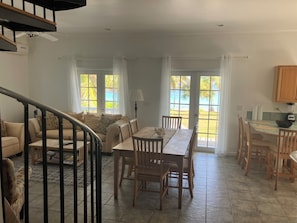 A spacious living area with a dining table, chairs, a sofa, and a staircase. - The Blue House,Oceanfront with 4 bedrooms 2 bath sleeps 10 in beds, water access (Spanish Wells)