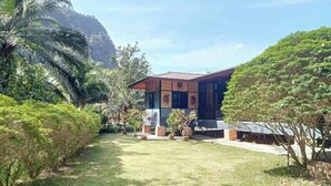 A modern building with a flat roof, surrounded by lush greenery and a mountain in the background. - Room-peaceful House Surrounding by Natur (Ao Luek)