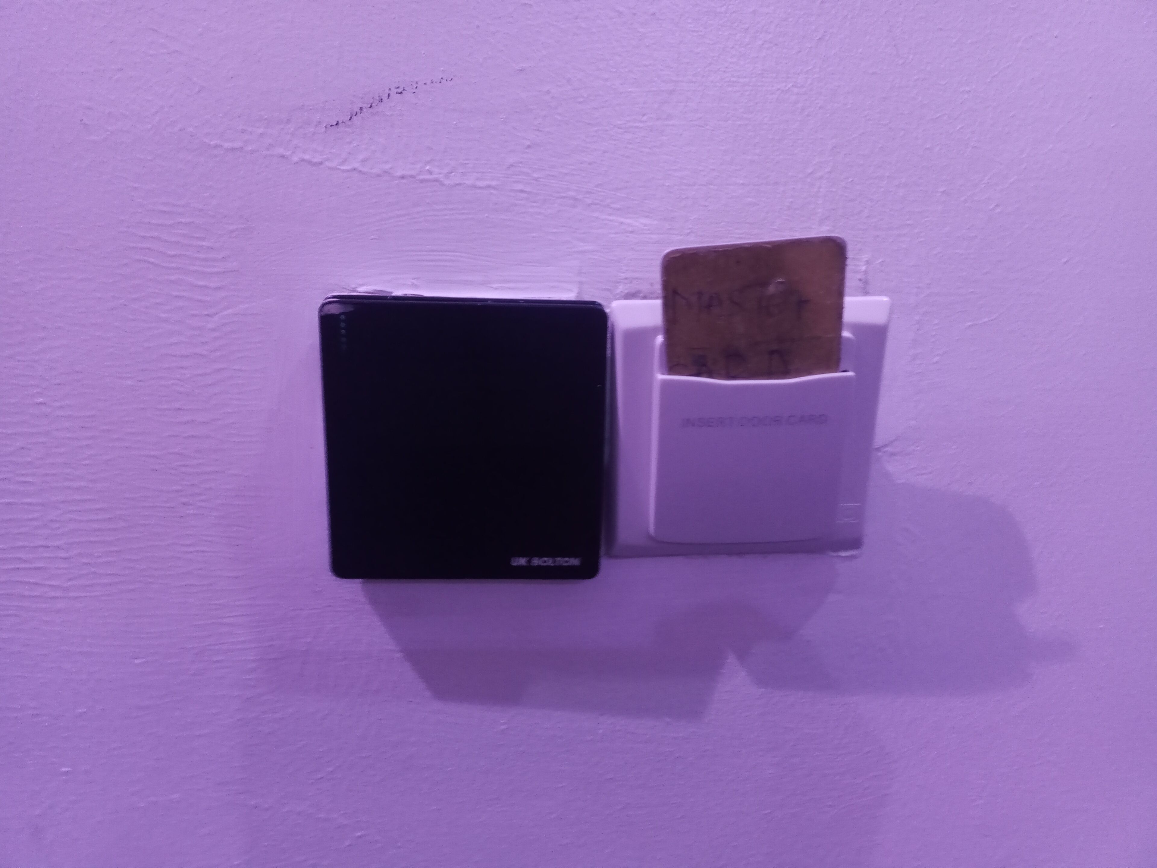 A black device mounted on a wall with a white card slot labeled "INSERT DOOR CARD".