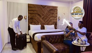Een hotelkamer met een bed, nachtkastje, stoel en koffer.
