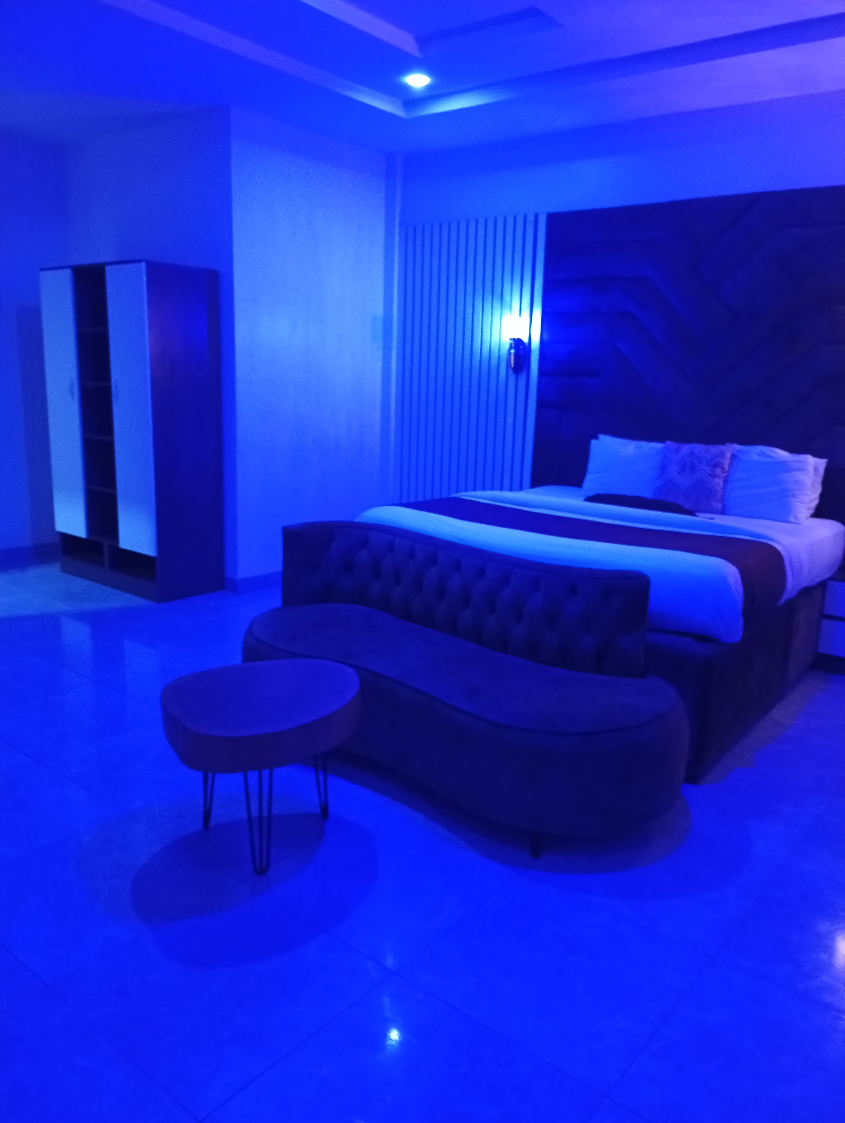 A bedroom with a bed, a sofa, a small table, and a wardrobe.