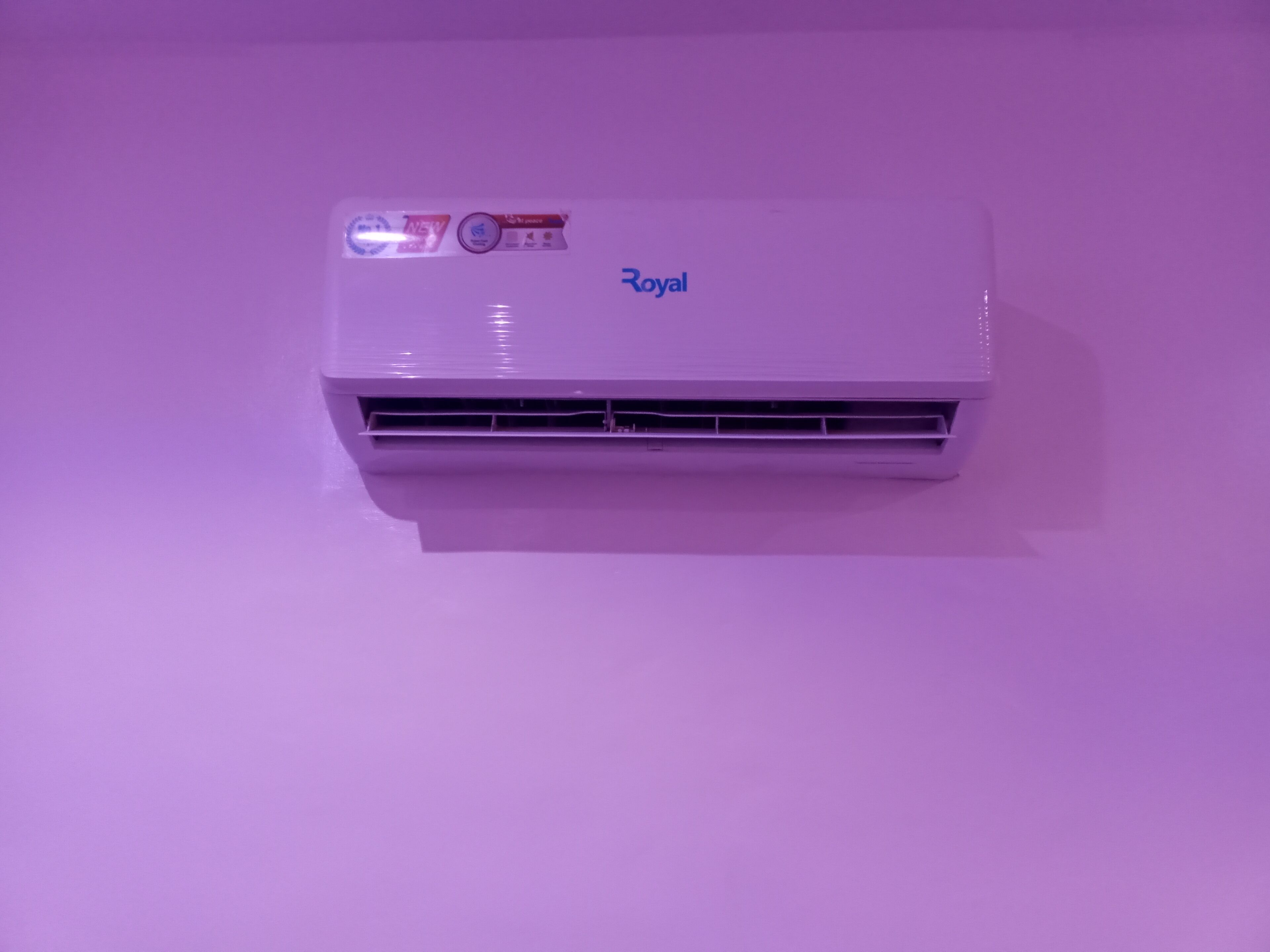 A white air conditioning unit with the brand name "Royal" on a purple background.