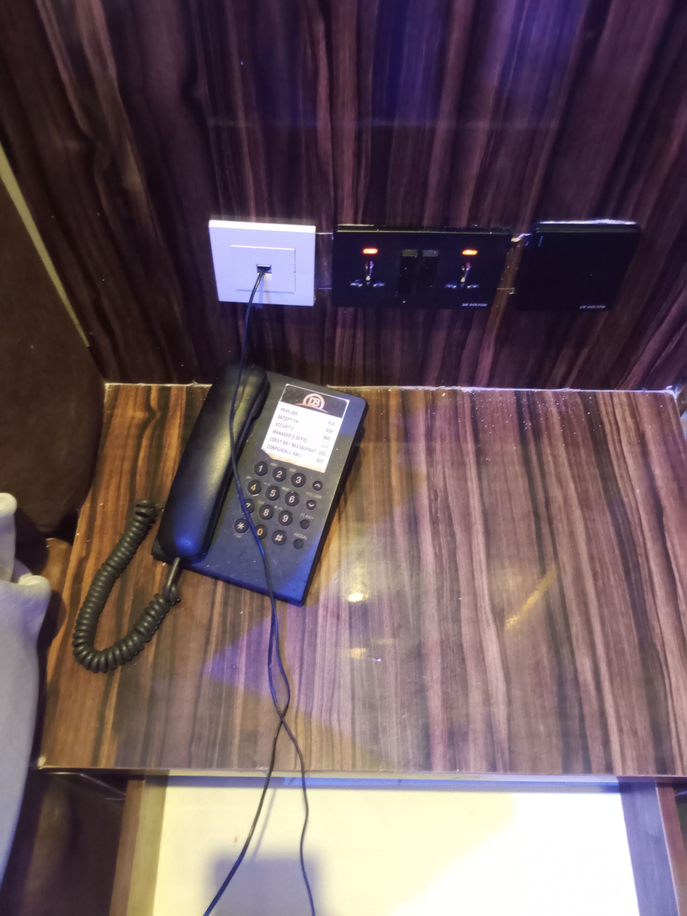 Un comptoir de réception d’hôtel équipé d’un téléphone, d’une prise électrique et d’un panneau lumineux.