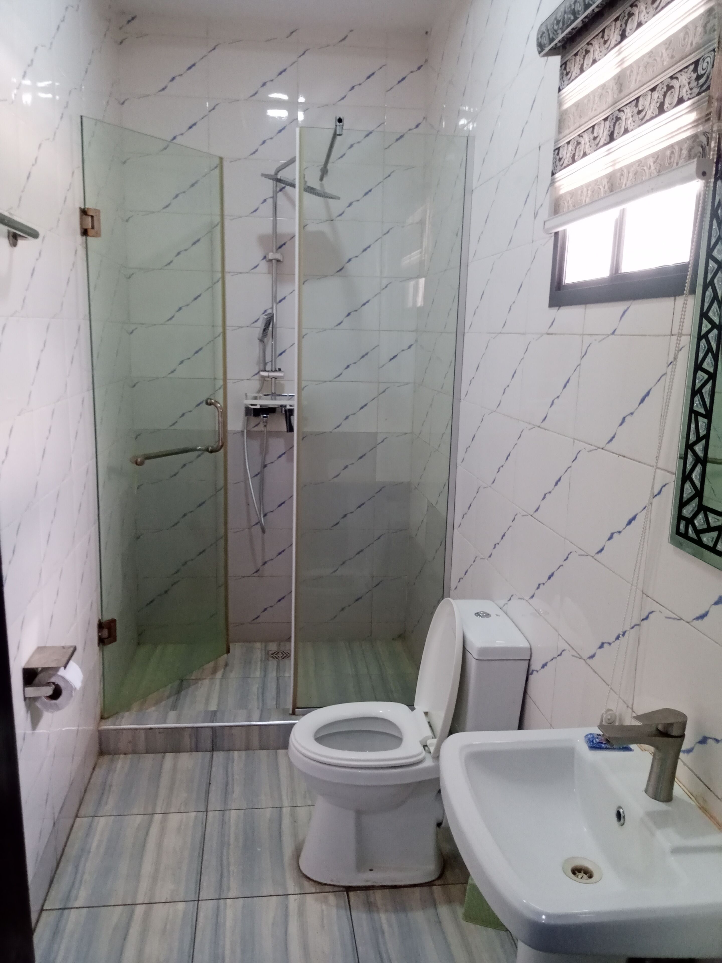 A bathroom with a glass-enclosed shower, a toilet, and a sink.