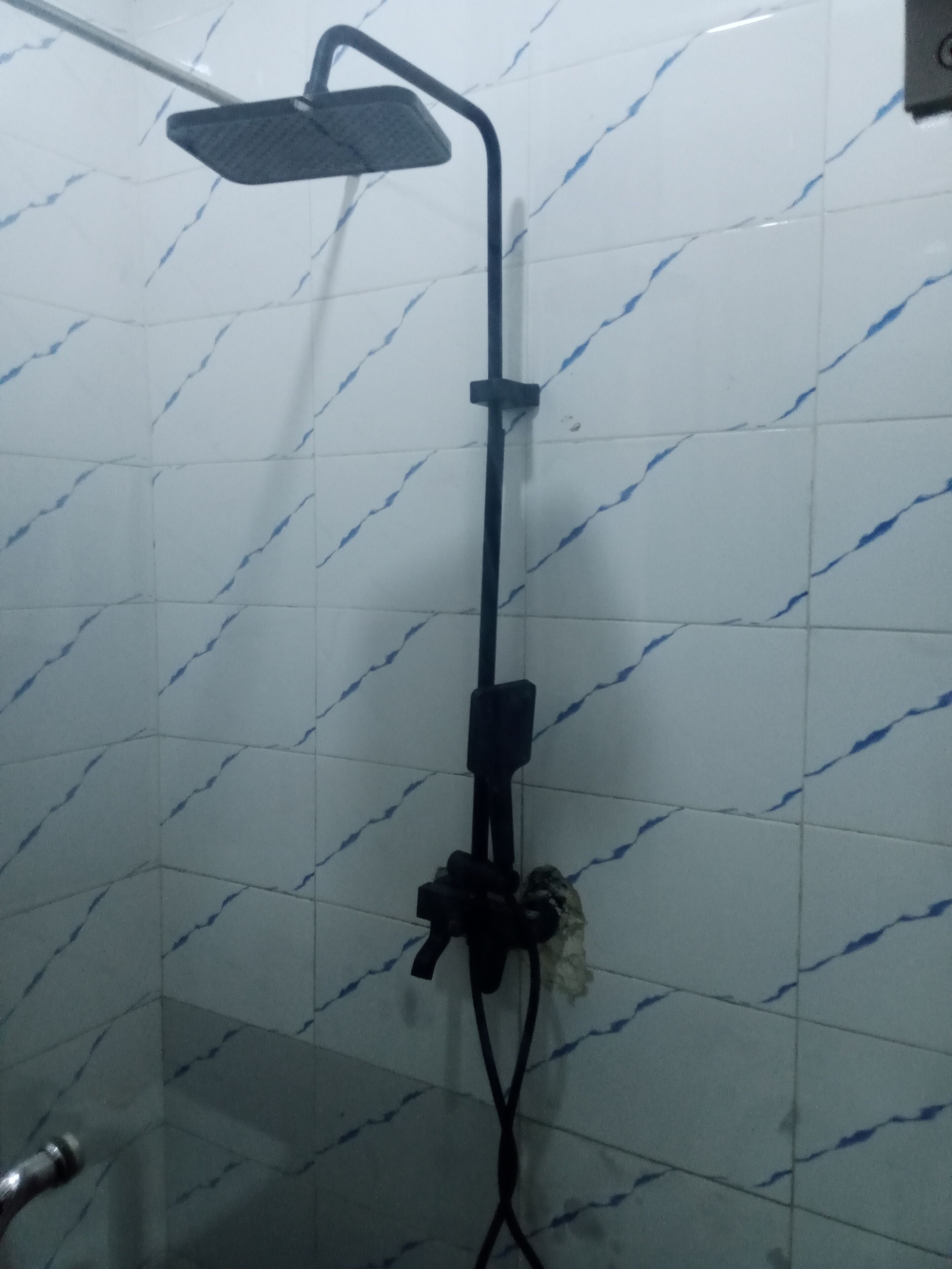 A shower with a handheld showerhead and a fixed overhead showerhead, mounted on a wall with a white and blue marble pattern.