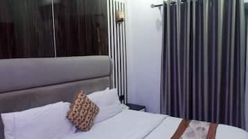 Una habitación de hotel con una cama, una mesita de noche, un espejo y una cortina.