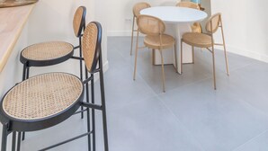 A modern dining area with a round table and four chairs, a small side table, and a potted plant. - Apartment RDC Arena Gare center (Reims)