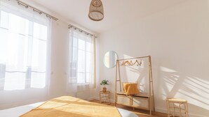 A bright bedroom with a bed, a small table, a chair, a ladder, and a stool. - Apartment RDC Arena Gare center (Reims)