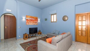 A living room with a sofa, television, and decorative items. - Apartment 'Lemon Terrace' with Private Terrace, Wi-Fi and Air Conditioning (Catania)